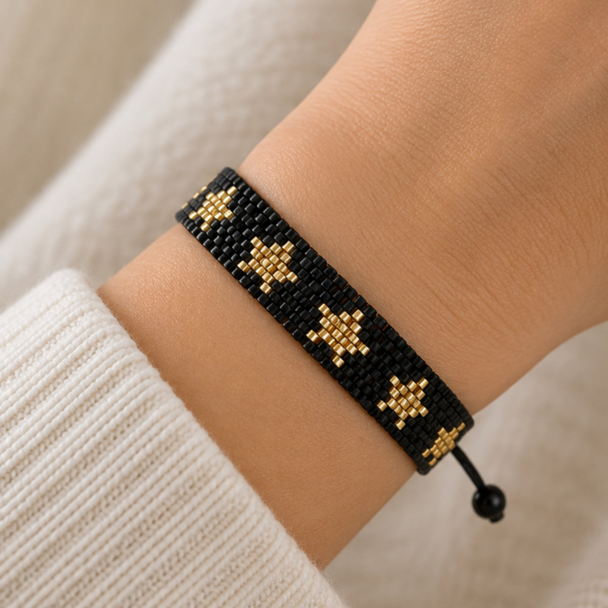 Pulsera de cuentas negra y dorada con estrellas en la muñeca.