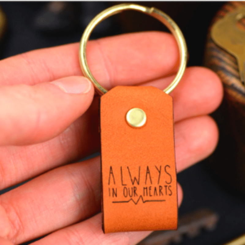 Llavero de cuero con frase “Always in our heart”, con anillo de latón y acabado elegante. Un detalle con valor emocional y duradero.