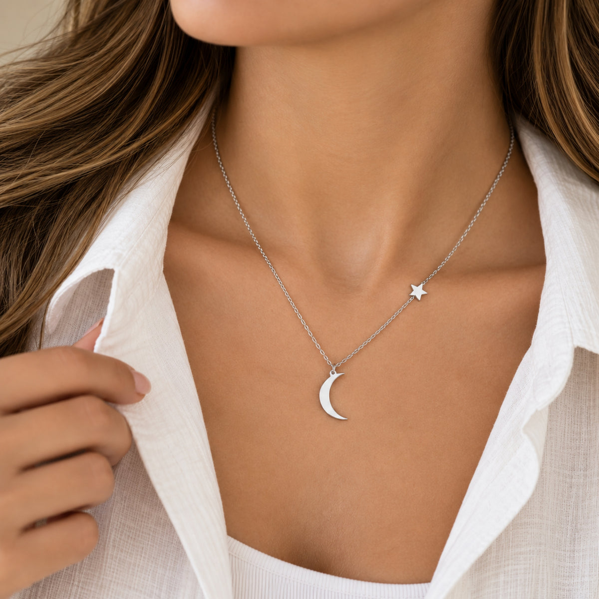 Collar de luna y estrella plateado usado con blusa blanca.
