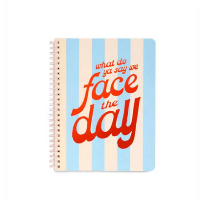 Cuaderno espiral "Face The Day" con 160 páginas rayadas, bolsillos dobles, espiral metálico de colores y frase inspiradora en la portada.