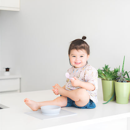Cuchara ergonómica para bebé zurdo en colores blanco y rosado. Diseño curvo para facilitar la autoalimentación.