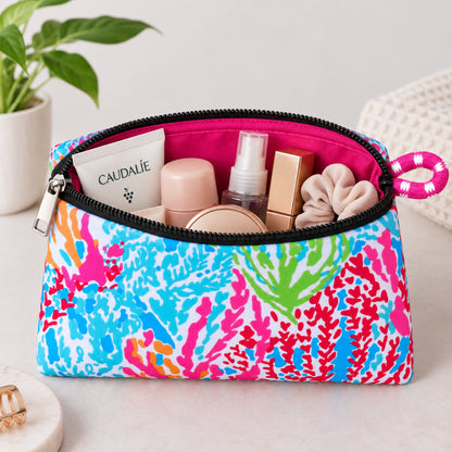 Neceser de neopreno Corales con estampado multicolor, cierre negro y productos de cuidado personal en su interior.