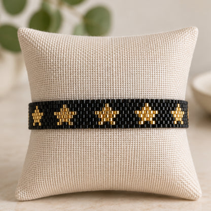 Pulsera de cuentas negra y dorada con diseño de estrellas.