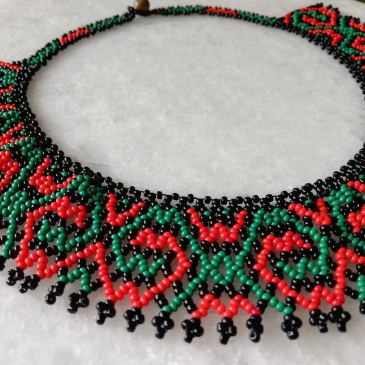 Collar de cuentas hecho a mano en tonos verde y coral, artesanía peruana, diseño colorido y elegante.